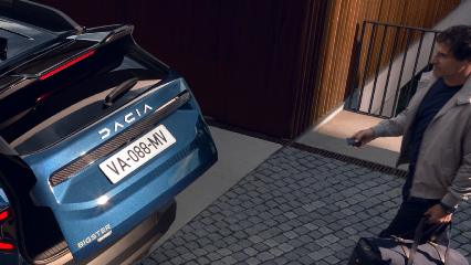 Condutor a abrir a porta da bagageira elétrica mãos-livres na traseira de um Dacia Bigster azul