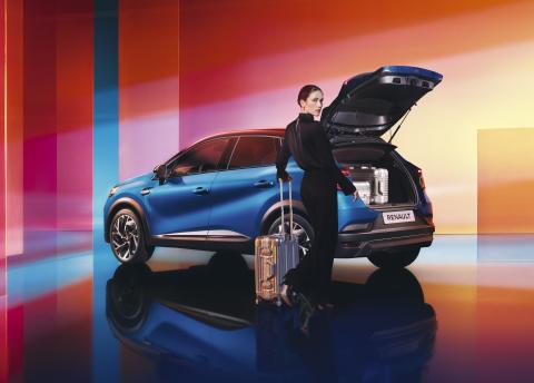 Renault Captur in blue, side view with the tailgate open and cabin suitcases being loaded into the boot